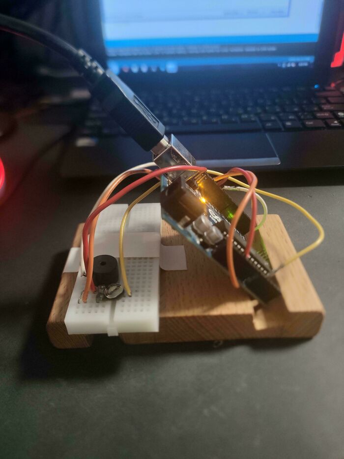Close-up of a messy electronics setup with wires and circuit board on a wooden base, highlighting soldering challenges.