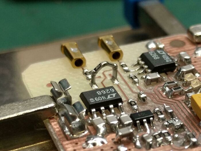 Close-up of a circuit board with poorly soldered electronic components and damaged connections being handled incorrectly.