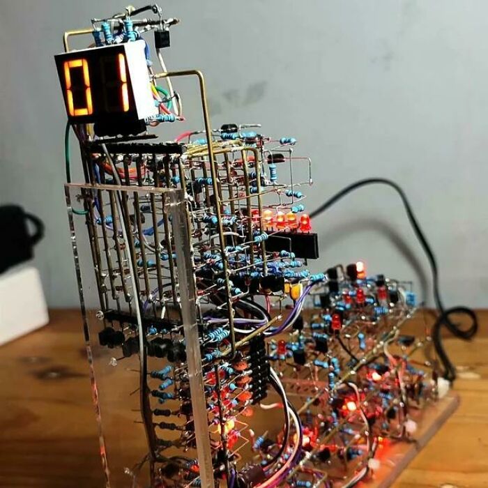 Complex electronic circuit with resistors and LED displays, showcasing soldering and handling of electronics components.