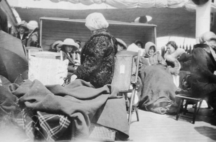 Passengers wrapped in blankets sitting on deck chairs aboard Titanic in a rare historical photo capturing life on the ship.