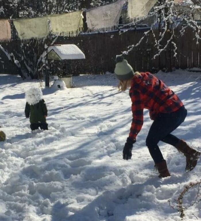 Child covered in snowball about to hit them as they play in the snow, capturing the split second before disaster hits hilariously.