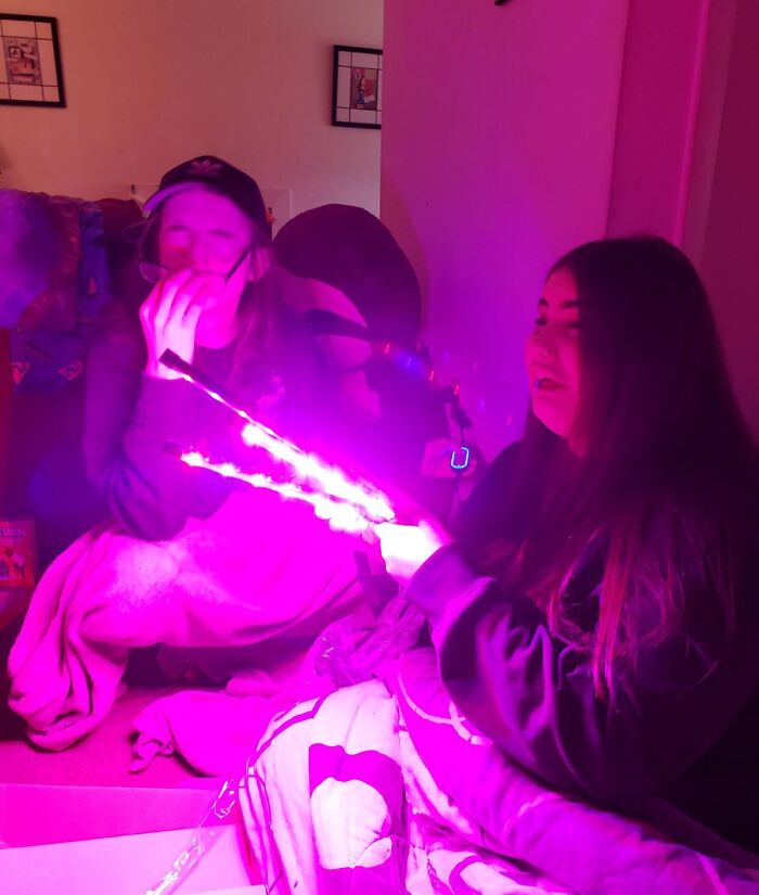 Two girls in a room illuminated by bright pink light, capturing the moment the rope broke just before disaster struck.