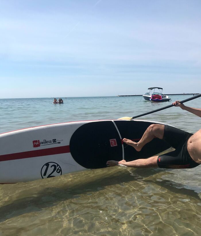 Man losing balance on paddleboard in shallow water capturing the split second before disaster hits hilariously.