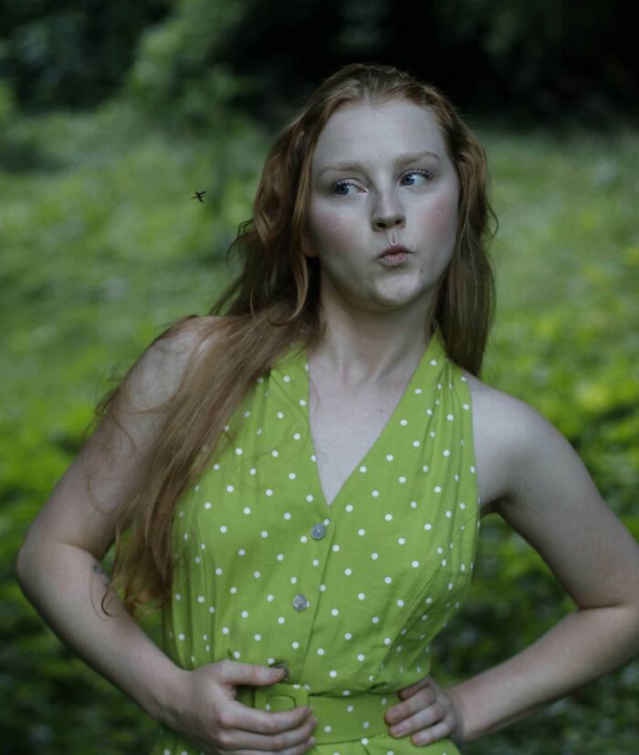 Young woman in a green polka dot dress reacting in the split second before disaster hits outdoors with a bug nearby
