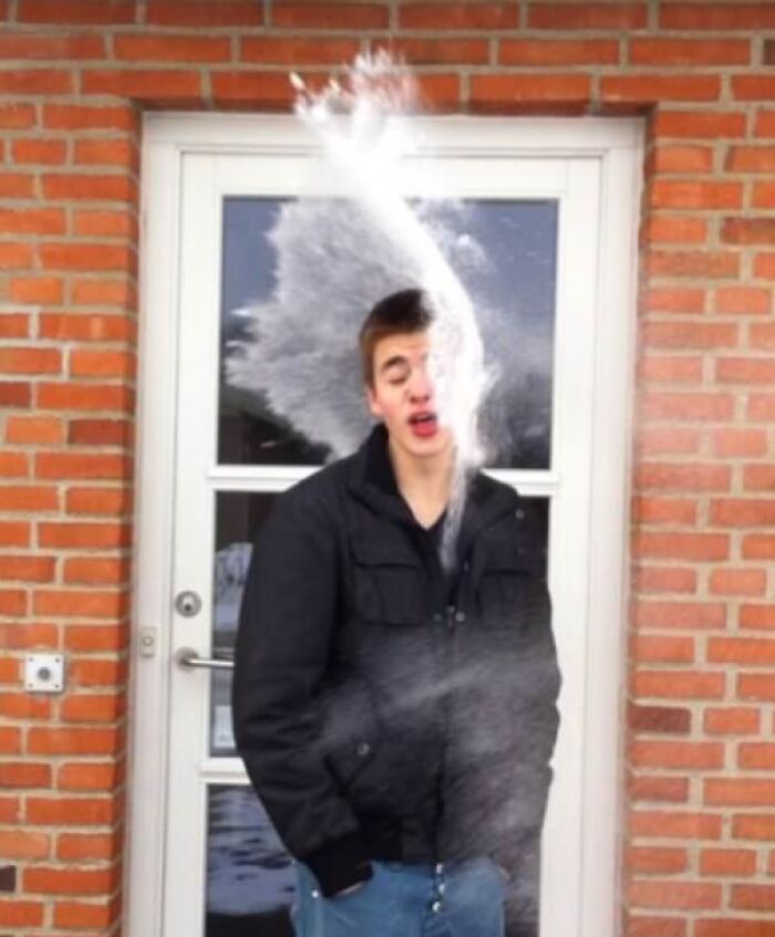 Young man captured in a split second before disaster as a splash of powder hits his face outside a brick building.