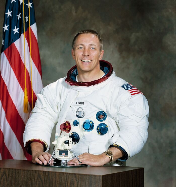 Astronaut in space suit posing with American flag and lunar module model illustrating famous historical quotes misconception.