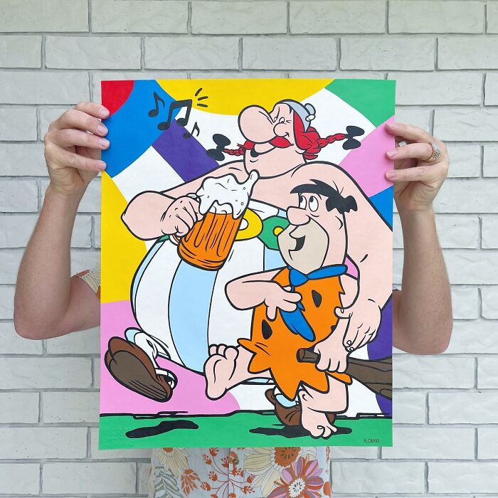 Colorful pop culture and cartoon character mash-up artwork held by a person in front of a brick wall background.