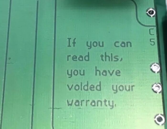 Close-up of a green circuit board with a warning about voiding warranty, illustrating poor electronics handling.