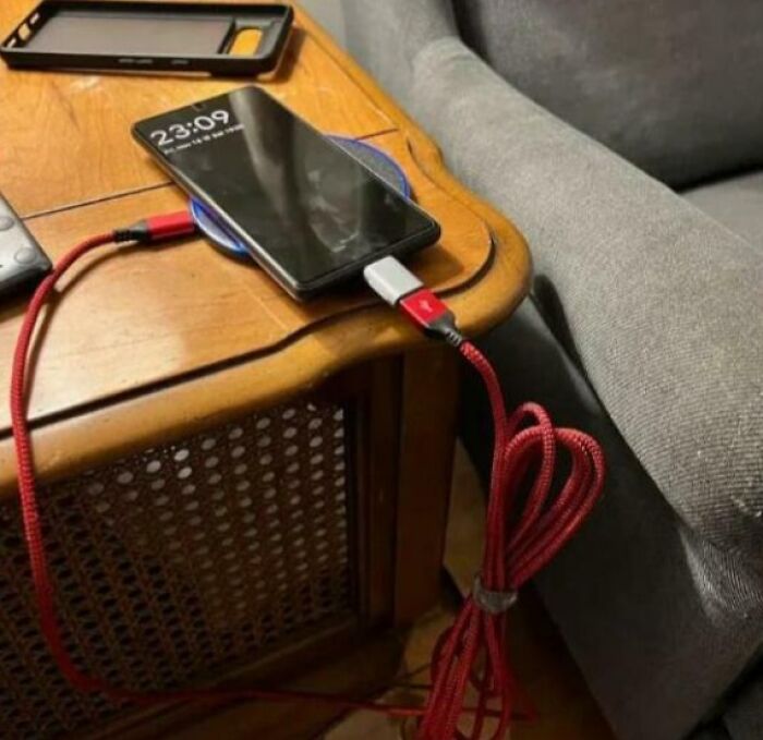 Smartphone plugged in with an extension cable awkwardly soldered, illustrating common mistakes in handling electronics.