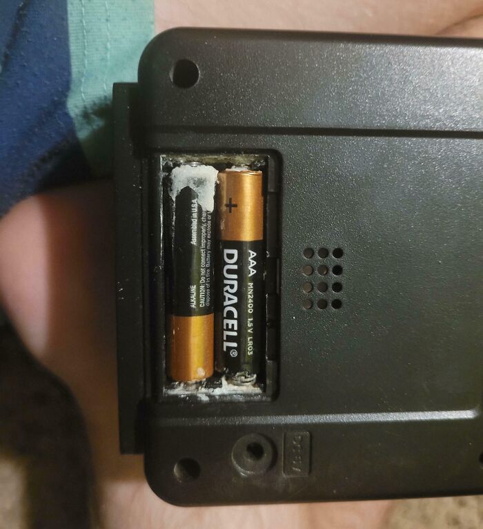 Battery compartment with leaking AAA batteries causing corrosion, illustrating risky electronics handling mistakes.