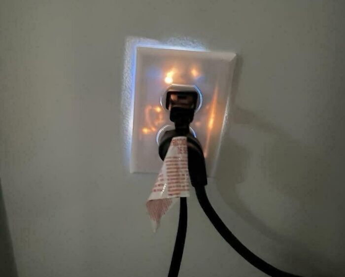 Electrical outlet sparking with damaged plug and tape, illustrating painful electronics handling mistakes and potential hazards.