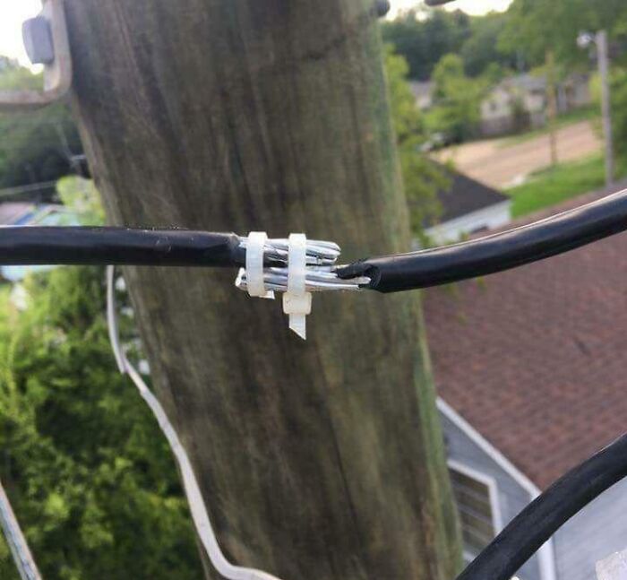 Exposed electrical wires loosely joined with plastic cable ties outdoors, illustrating improper handling of electronics.