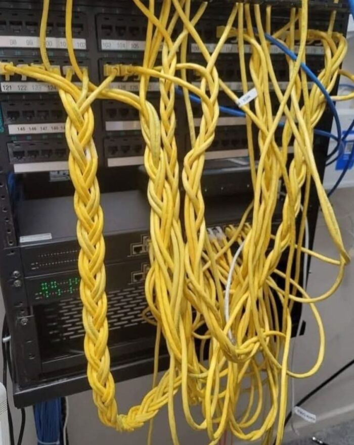 Tangled yellow Ethernet cables twisted together haphazardly in a server rack showing poor electronics handling.