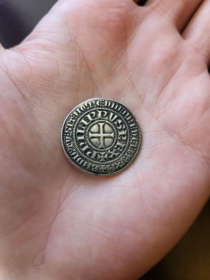 Close-up of a hand holding a detailed medieval coin, a treasure for medieval history enthusiasts and collectors.