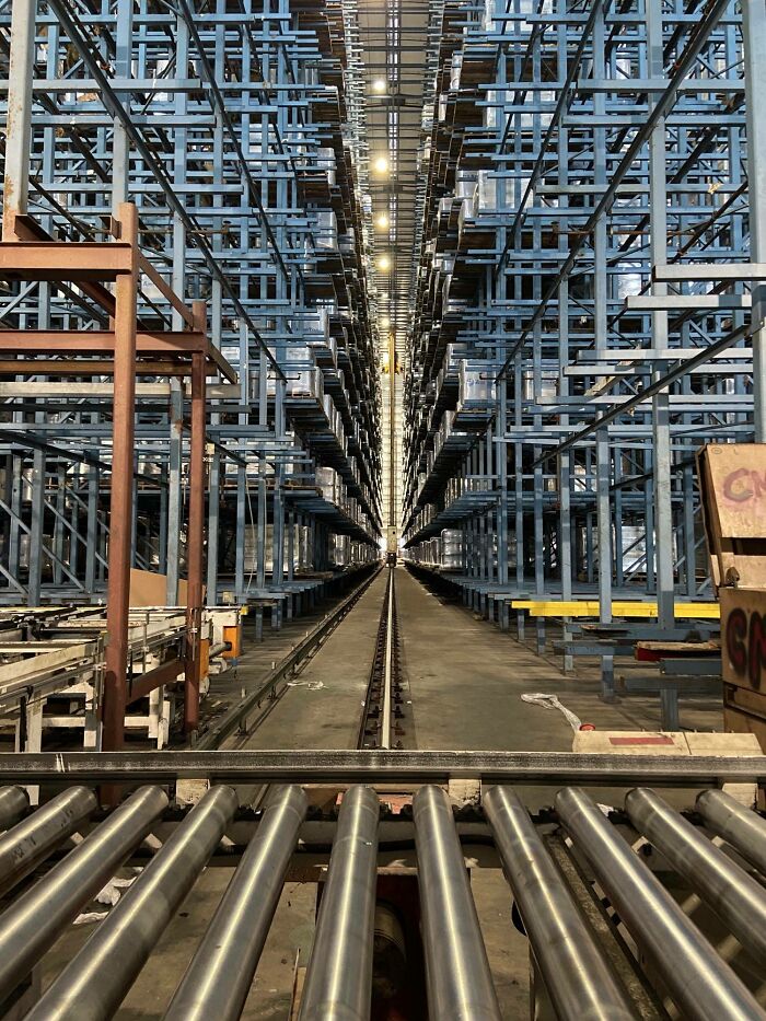 Warehouse storage racks and conveyor system creating a creepy and unsettling industrial work environment.