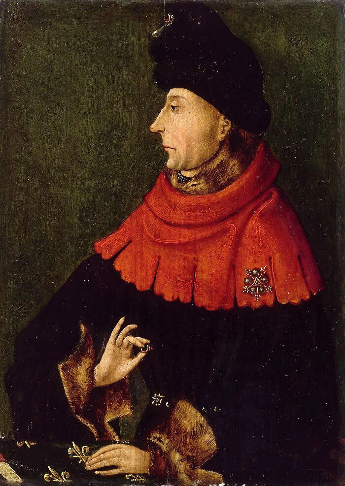 Medieval history enthusiast portrait wearing a red cloak and black hat with fur details and ornate brooch.