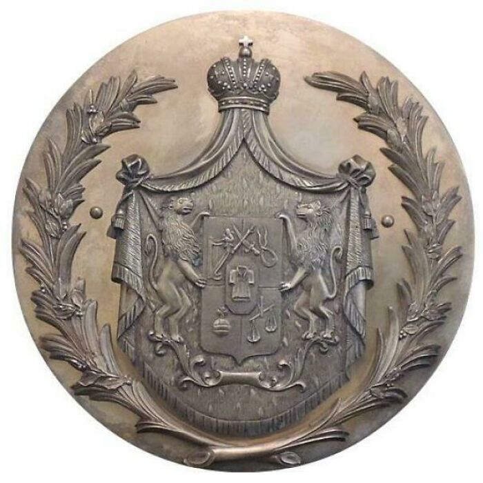 Medieval history emblem featuring a crowned shield with lions and symbolic medieval motifs in a decorative wreath.