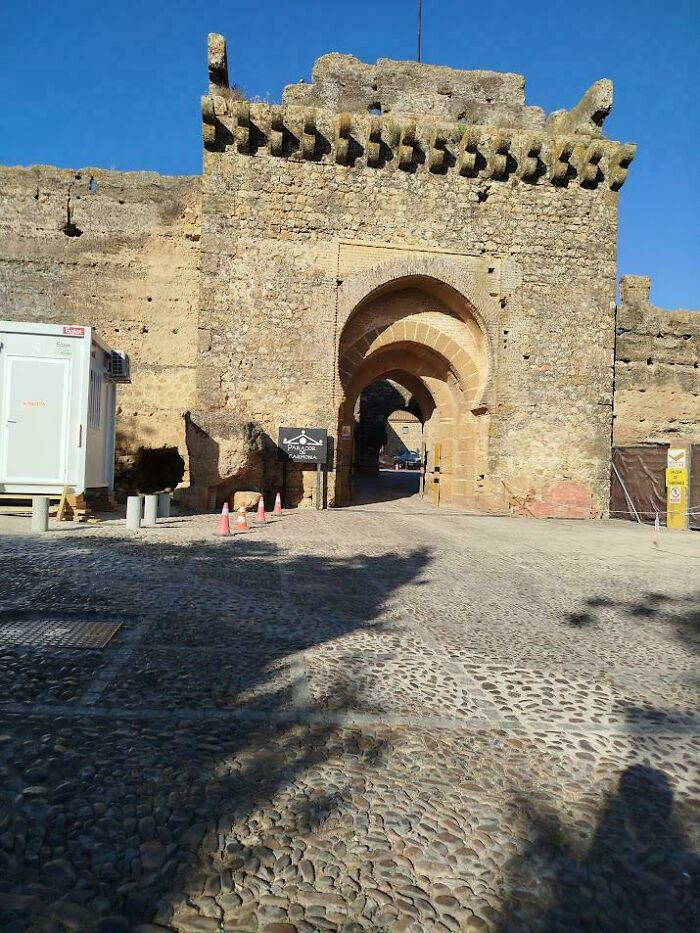Medieval history enthusiasts exploring an ancient stone fortress entrance under clear blue skies.