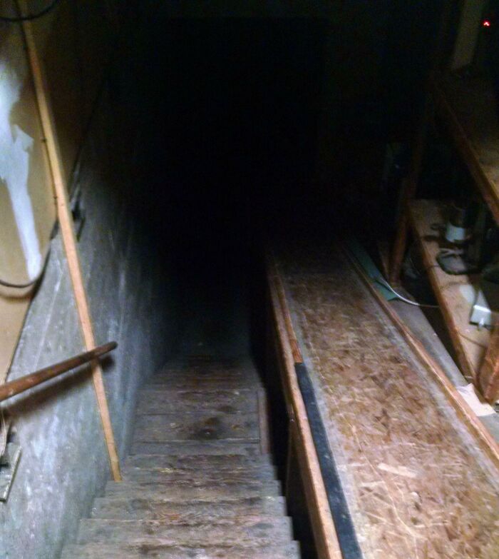 Dark, narrow basement stairs descending into shadowy tunnel, highlighting creepy and unsettling work environments in jobs that should pay more.