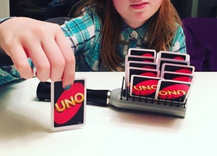 Child with inventive card holder playing UNO, showcasing creativity and smart invention surprising parents with new ideas.
