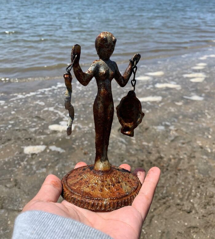 Rusty old metal figurine found on beach, an example of people discovering something old with no clues.