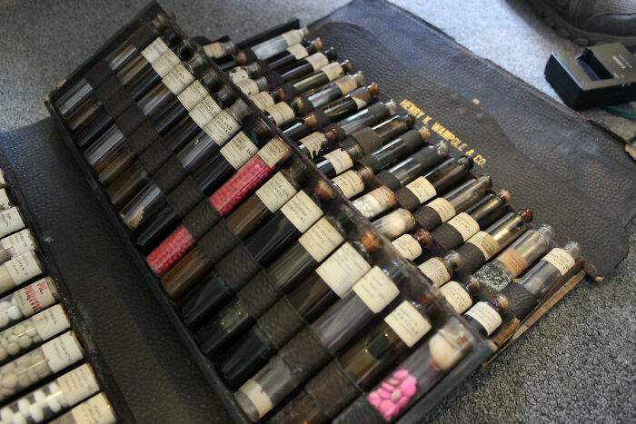 Old collection of labeled glass vials and pills stored in a leather case, an unusual historic find with unknown purpose