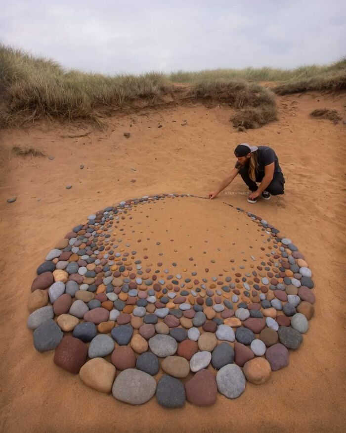 Artist Jon Foreman creating hypnotic land art with arranged stones on a sandy beach in Wales, showcasing sculpt the world.