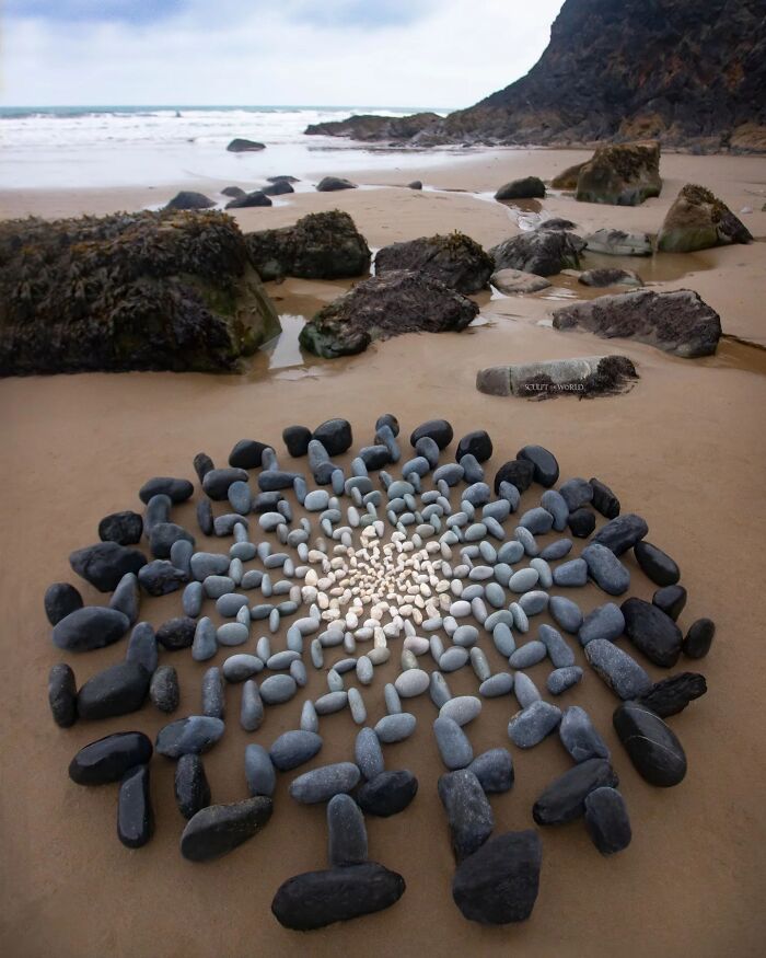 Stone spiral land art installation on a sandy beach in Wales, showcasing Jon Foreman’s hypnotic short-lived beach sculpture.