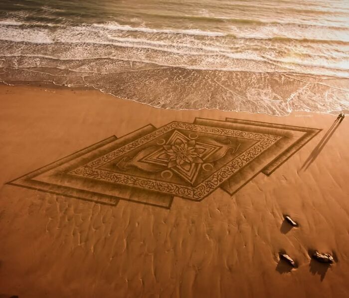 Hypnotic land art carved into the beach sand at Wales’s shore, showcasing intricate patterns and shapes by Jon Foreman.