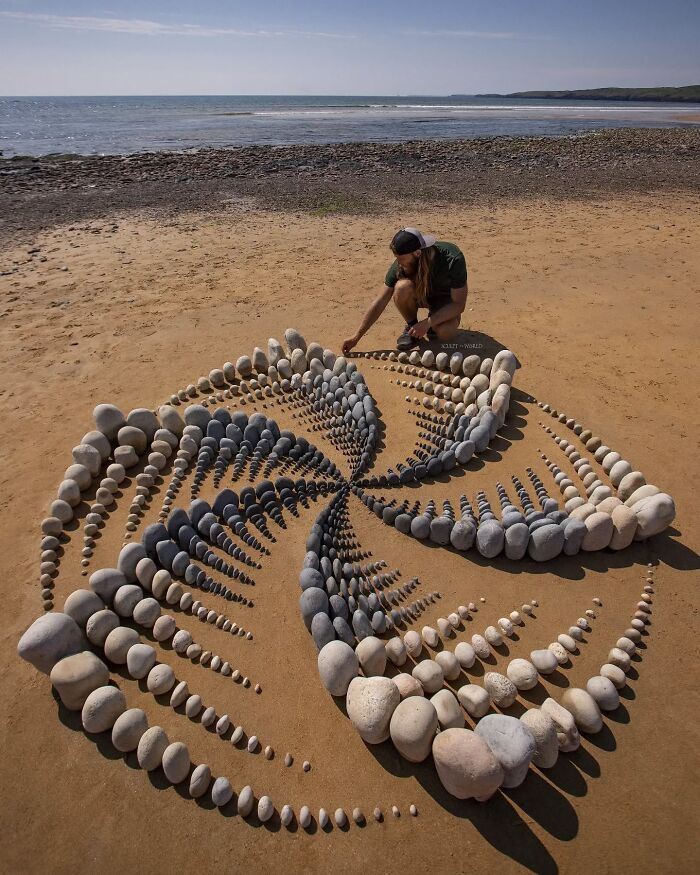 Artist Jon Foreman creating hypnotic land art with stones on a sandy beach in Wales, sculpting the world’s natural canvas.
