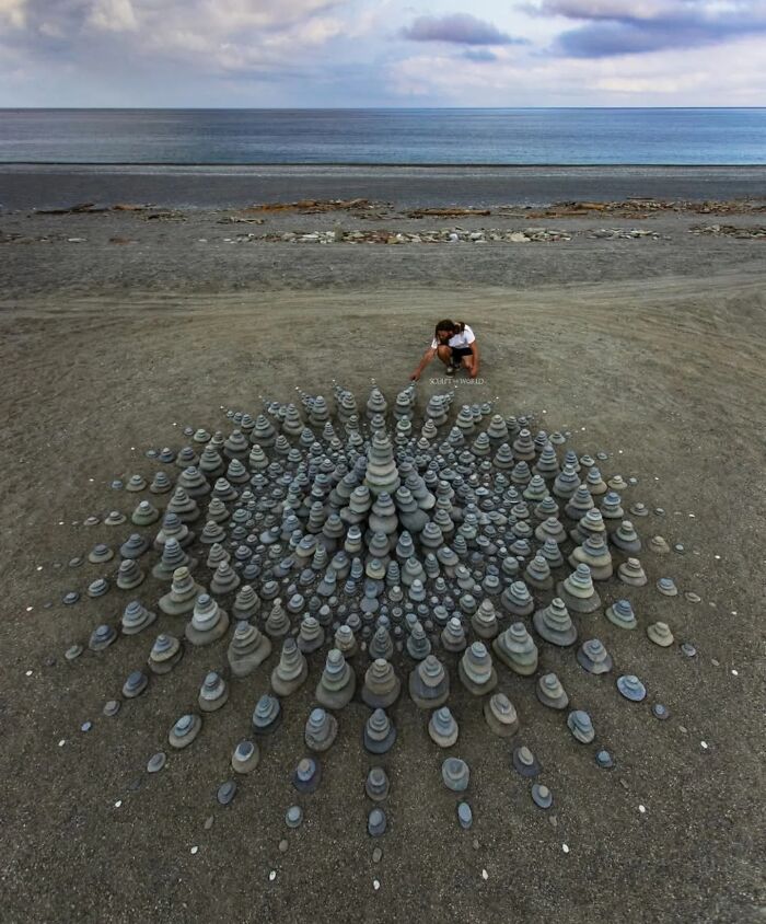 Artist Jon Foreman creating hypnotic, short-lived land art sculptures on a beach in Wales with stacked stones and patterns.