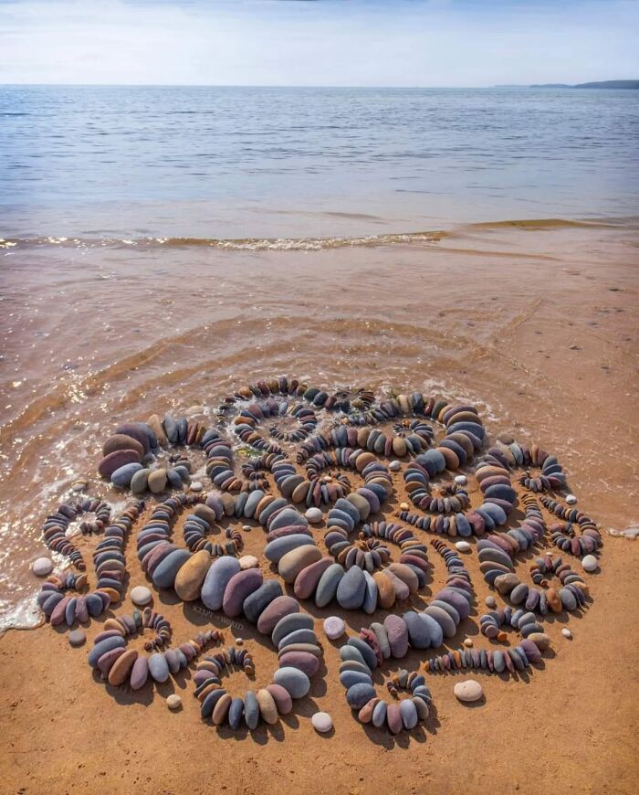 Hypnotic land art made of spiral stone patterns on a sandy beach in Wales, created as short-lived sculpture.