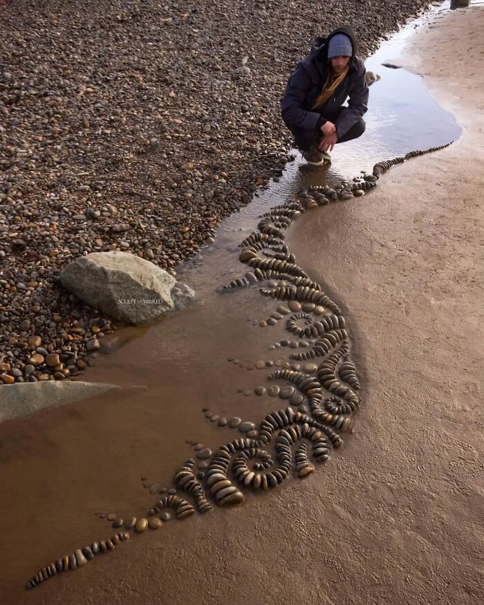 Artist Jon Foreman crouches by hypnotic, short-lived land art made of arranged stones on a beach in Wales.