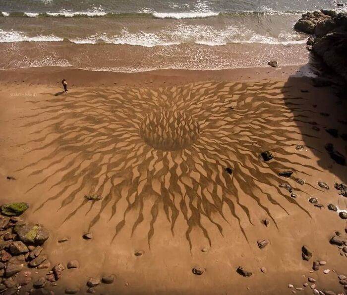 Land art on a beach in Wales by Jon Foreman featuring hypnotic patterns carved into the sand near the water’s edge.