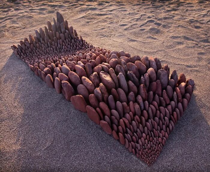 Hypnotic land art sculpture made from smooth stones arranged on a sandy beach in Wales by Jon Foreman.