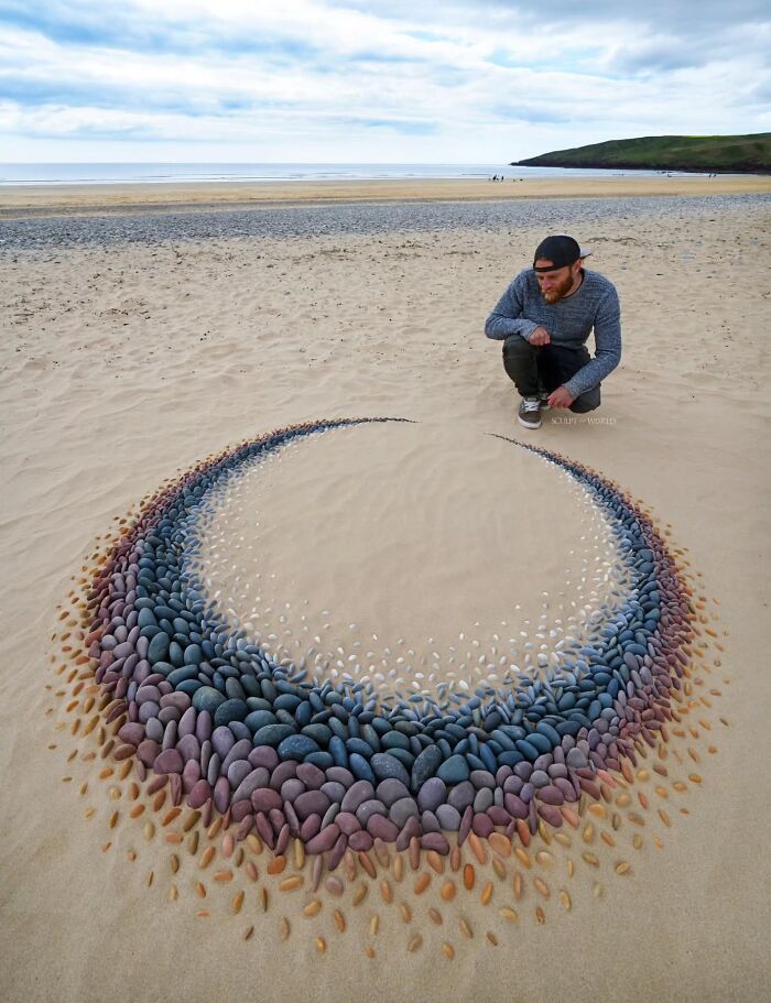 Artist Jon Foreman creating hypnotic land art with colorful stones on a sandy beach in Wales.
