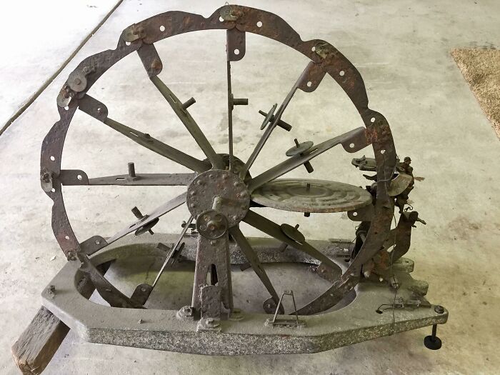 Rusty old metal wheel with spokes and mechanical parts, an antique object found but unknown to the finder.