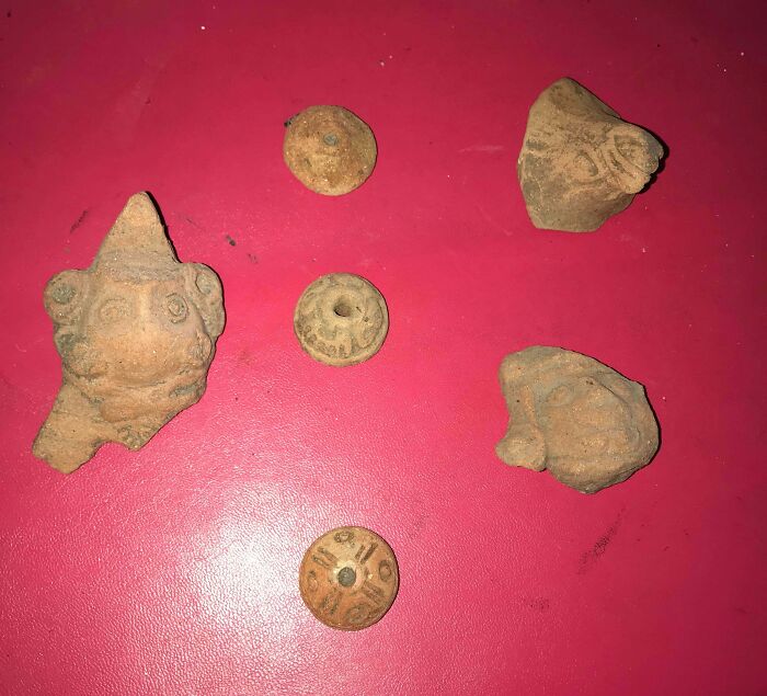 Old artifacts and ancient objects found, with no clue what they are, displayed on a red surface.