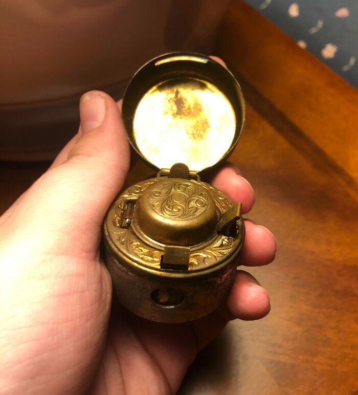 Hand holding an intricately designed old brass object, an example of finding something old with no clue what it is.