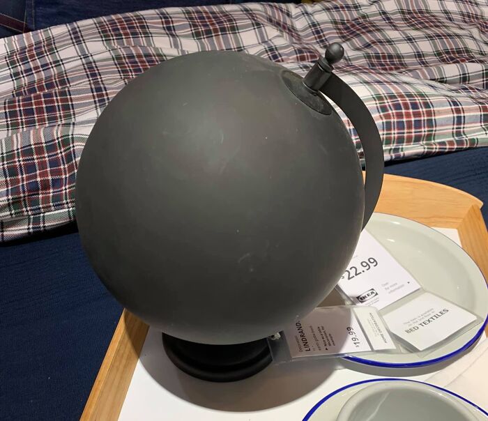 Black globe with no visible map details sitting on a tray, illustrating funny bad maps concept.