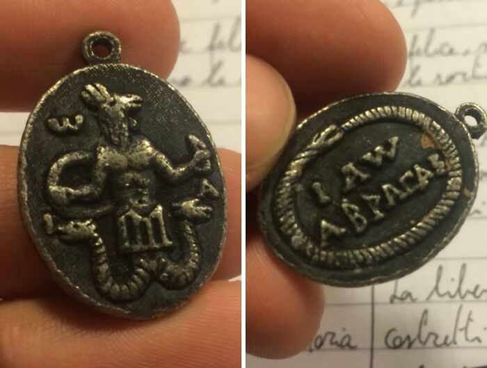 Old mysterious amulet found, archeological artifact with unclear symbols showing serpent and ancient inscriptions.