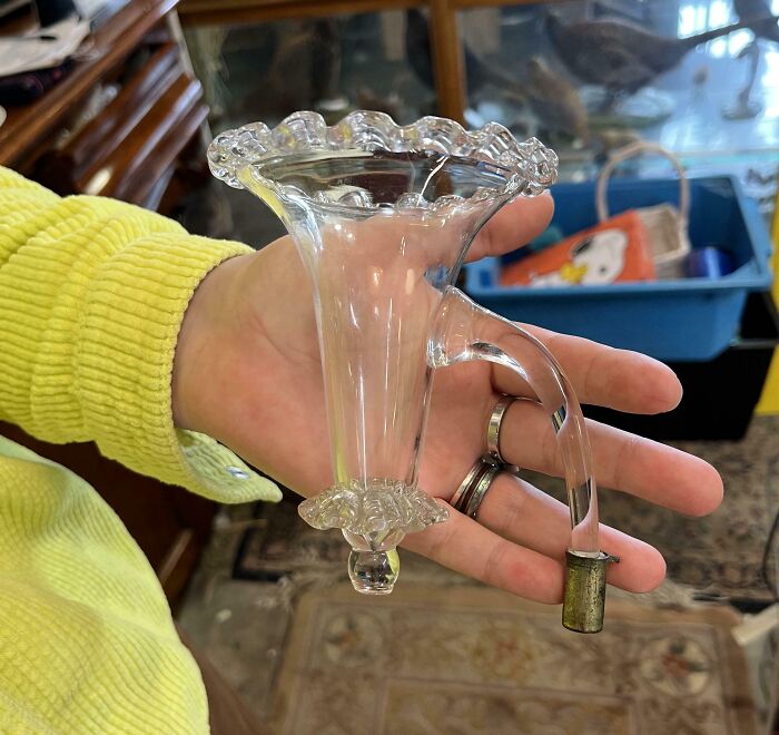 Hand holding an old vintage glass funnel with a curved spout, an antique item found but unrecognized by internet users.