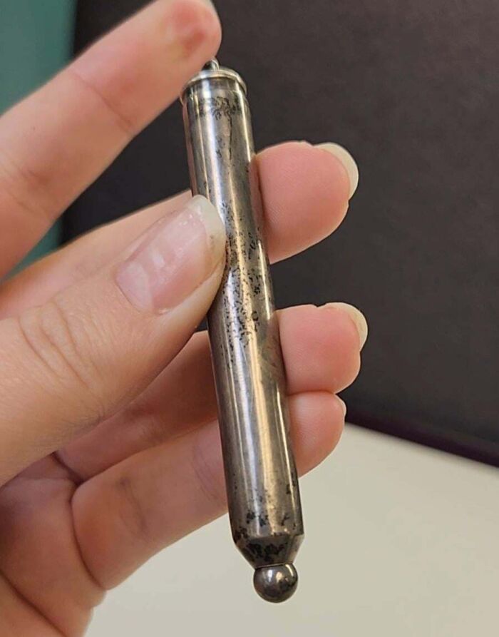 Hand holding an old metallic object of unknown purpose found by people sharing mysterious old finds online.