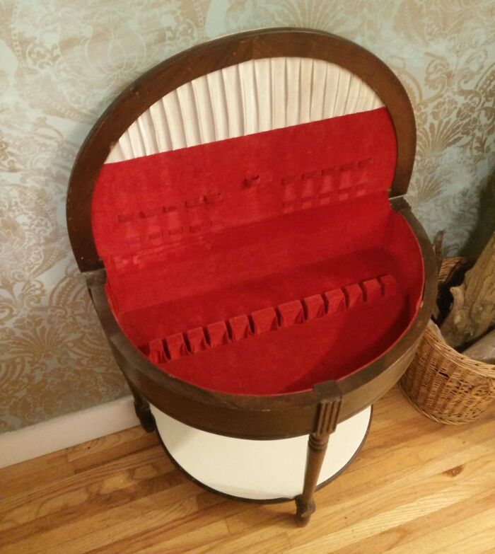 Vintage wooden jewelry holder with red velvet interior and multiple slots, an old item found with uncertain purpose.