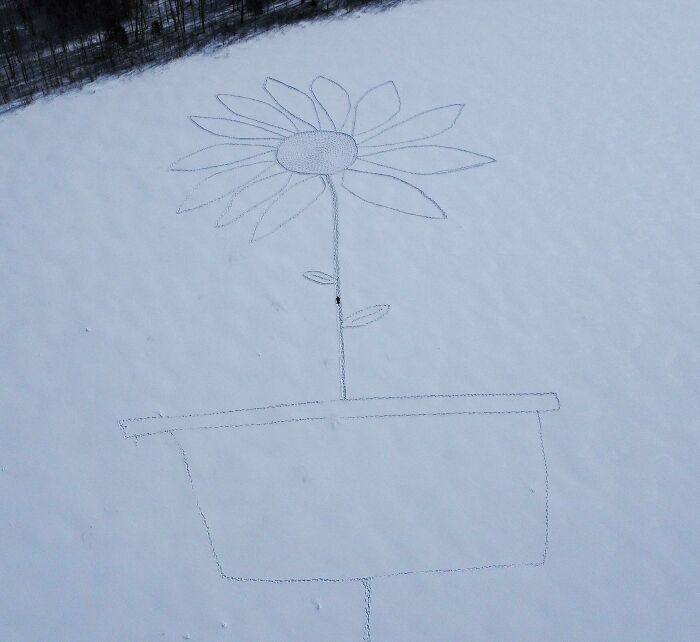A person standing in snow inside a giant flower and pot drawing, showing human for scale with unusual size comparison.