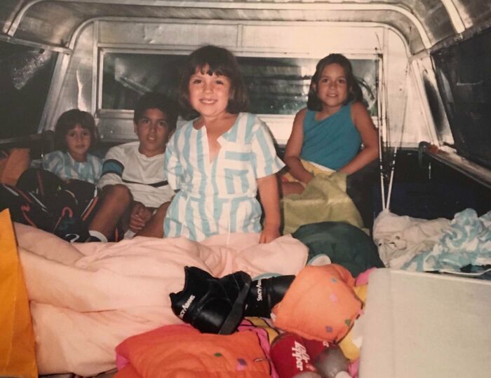 Group of kids smiling inside a vehicle during a vacation, capturing a moment from a time before cell phones had cameras.