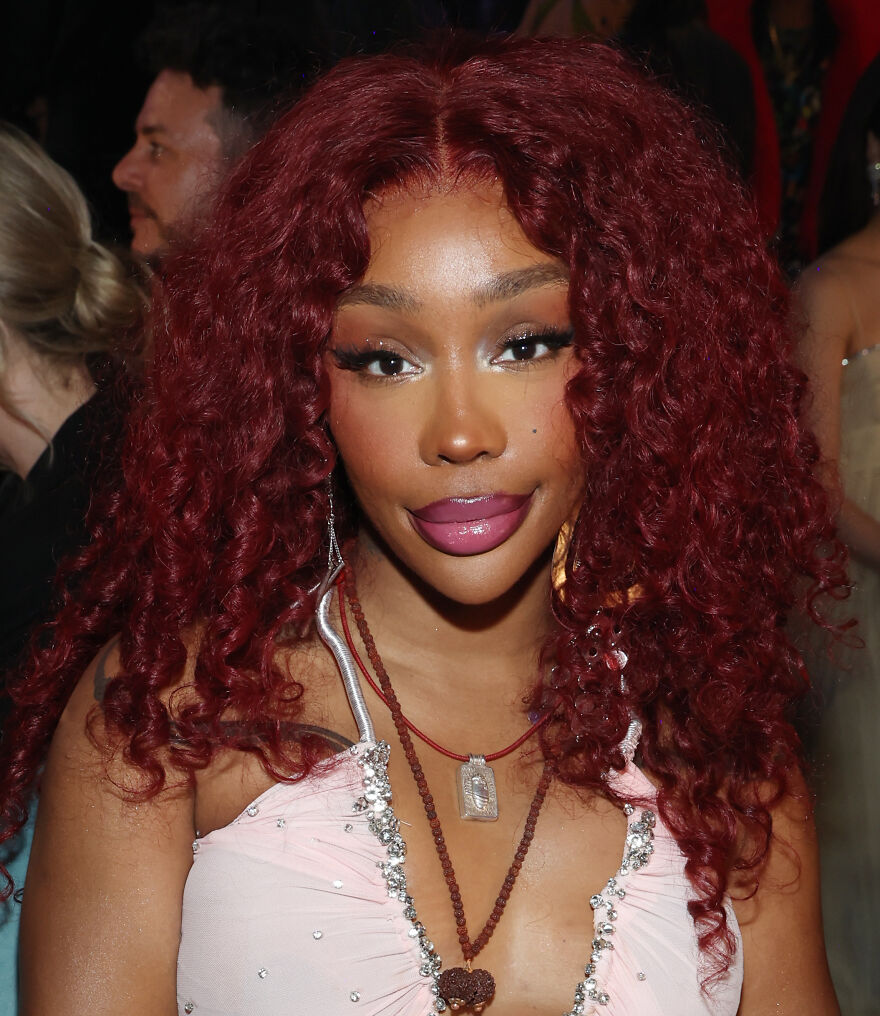 Sza with curly red hair and glam makeup showcasing cosmetic transformation at a social event in stylish attire. Sza with curly red hair and glam makeup showcasing cosmetic transformation at a social event in stylish attire.