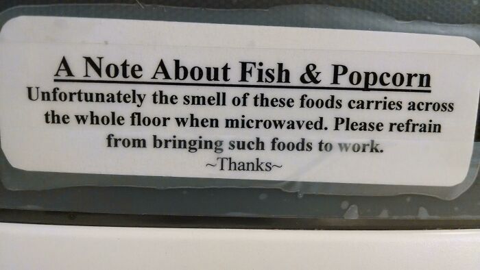 Passive-aggressive coworker note about the smell of fish and popcorn in the office microwave area.