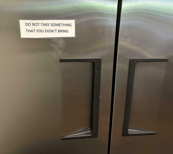 Passive-aggressive note on a stainless steel office fridge warning coworkers not to take items they didn’t bring.