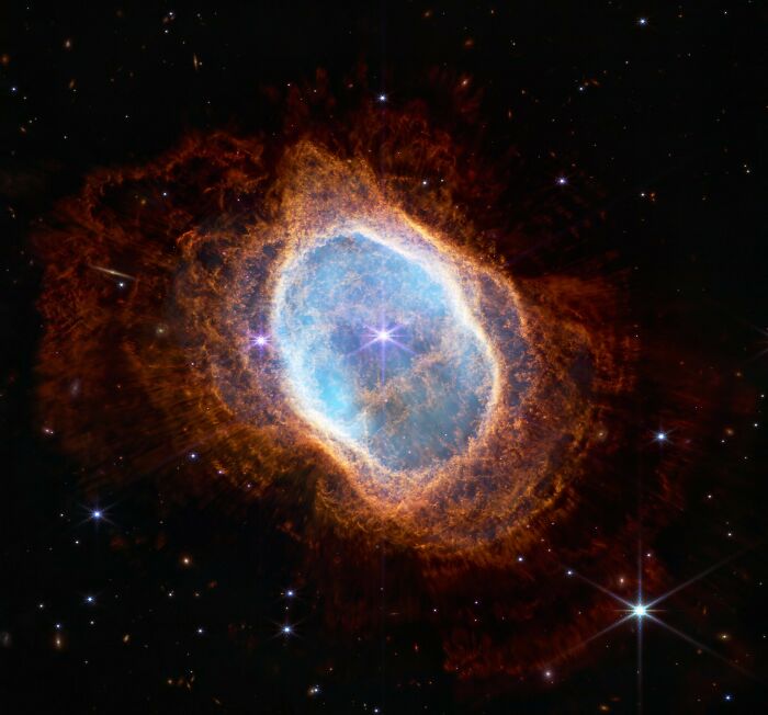 Glowing cosmic nebula with bright blue center and fiery orange outer rings, showcasing epic astronomy space beauty and mystery.